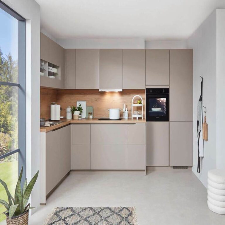 Musterküche in Kaschmir als L-Küche mit Holzrückwand und Backofen im Hochschrank – Küchenstudio Magdeburg